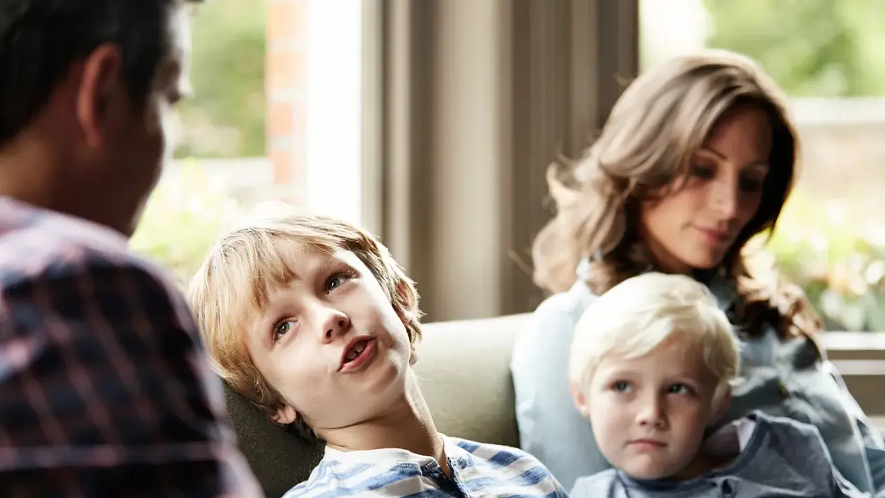 Ein Junge spricht mit seinem Vater, während seine Mutter und sein jüngerer Bruder zuhören. Eine Szene, die zeigt, wie Kinder mit der Trennung der Eltern umgehen.