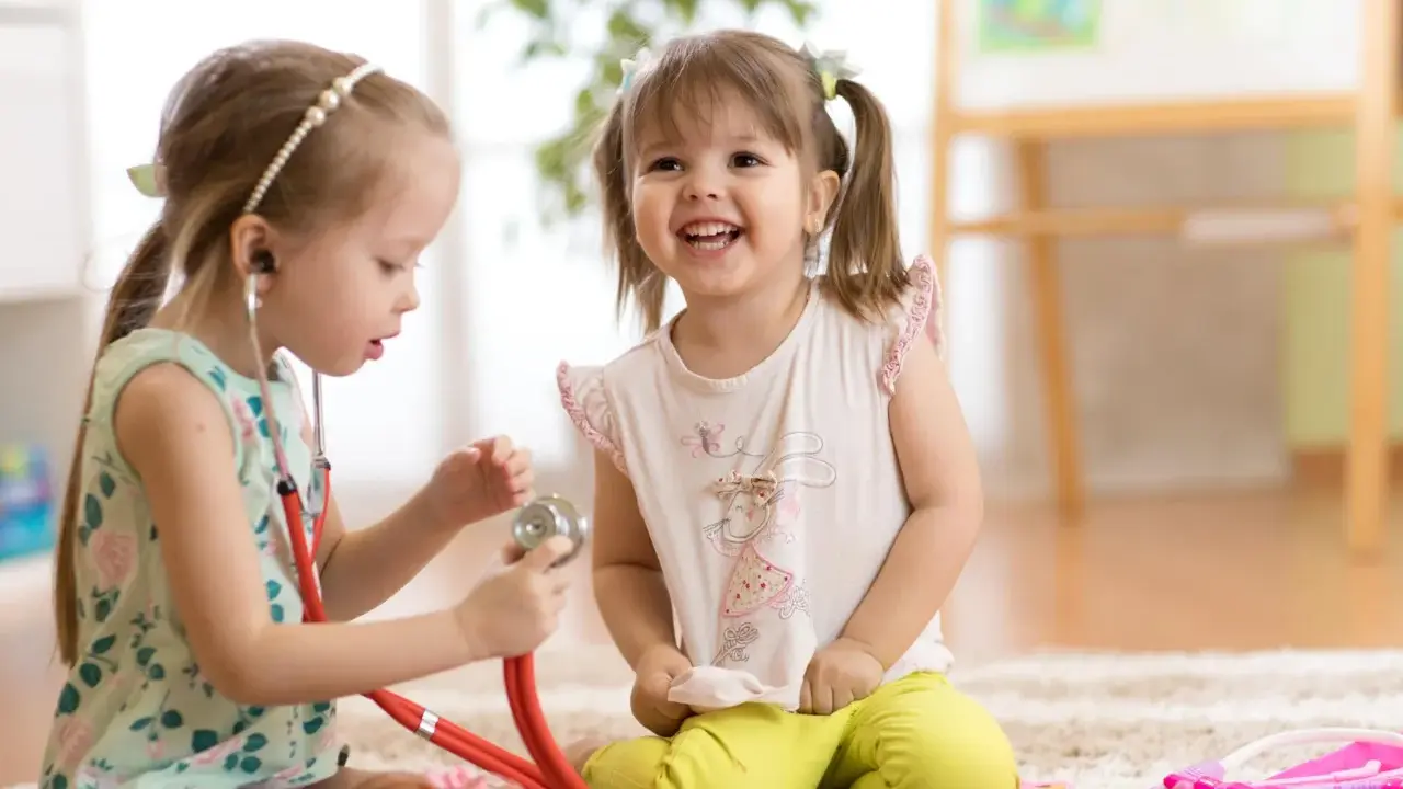 Zwei Mädchen spielen Arzt. Das eine Kind, etwa 7 Jahre alt, untersucht das andere mit einem Stethoskop. Ein spielerischer Einblick in die sexuelle Entwicklung eines Kindes.