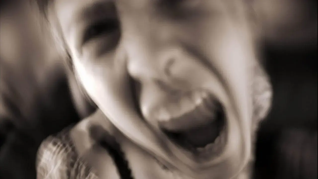 Verzweifeltes Gesicht, das schreit. Die Frage "warum bin ich so aggressiv zu meiner familie" hallt in der Stille wider.