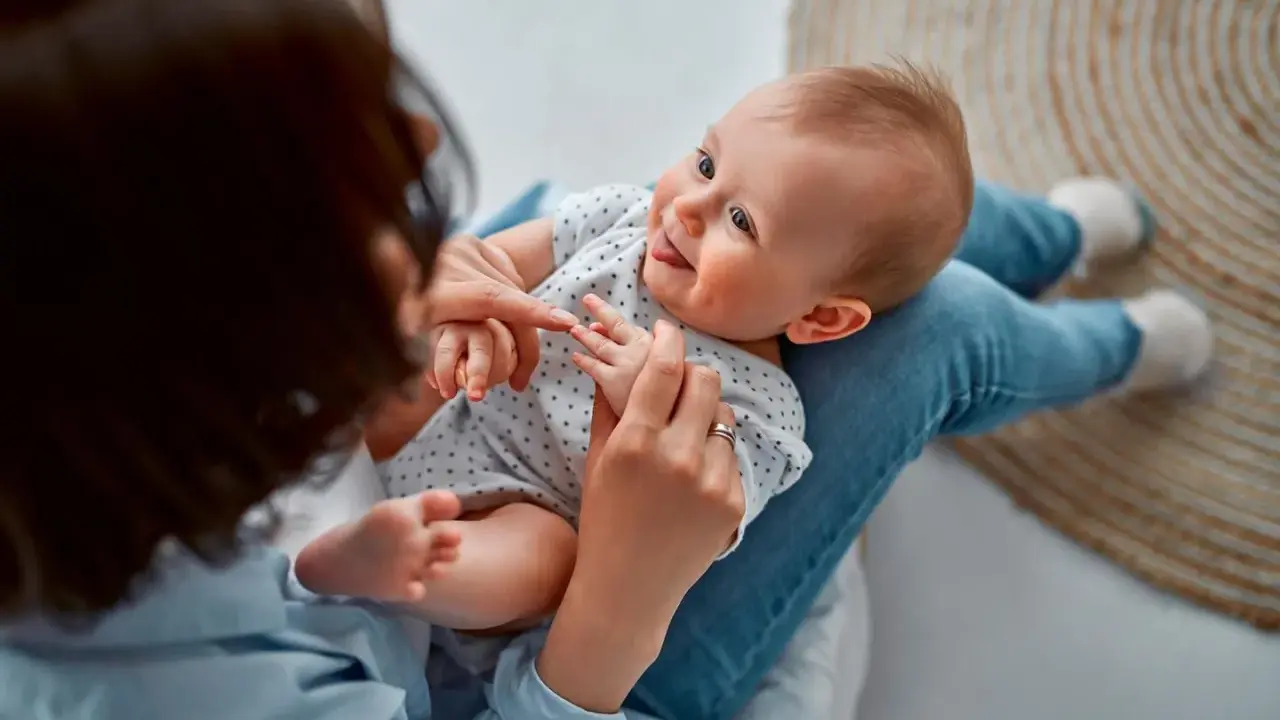 Ein Baby liegt auf dem Schoß einer Person. Vielleicht sucht die Person nach Inspiration für Jungennamen aus der Bibel.