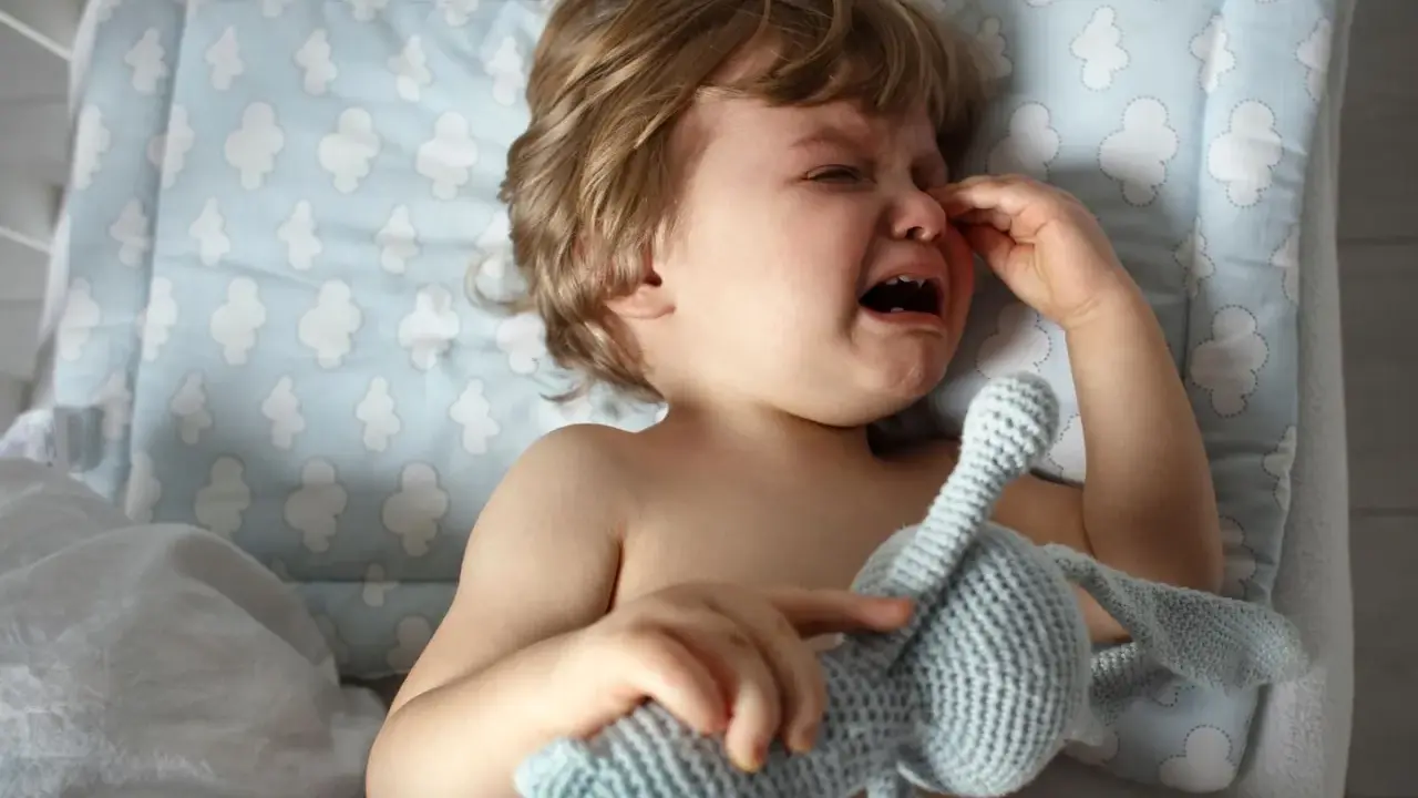 Ein weinendes Kind, 1 Jahr alt, in der Trotzphase, hält seinen Kuschelhasen.