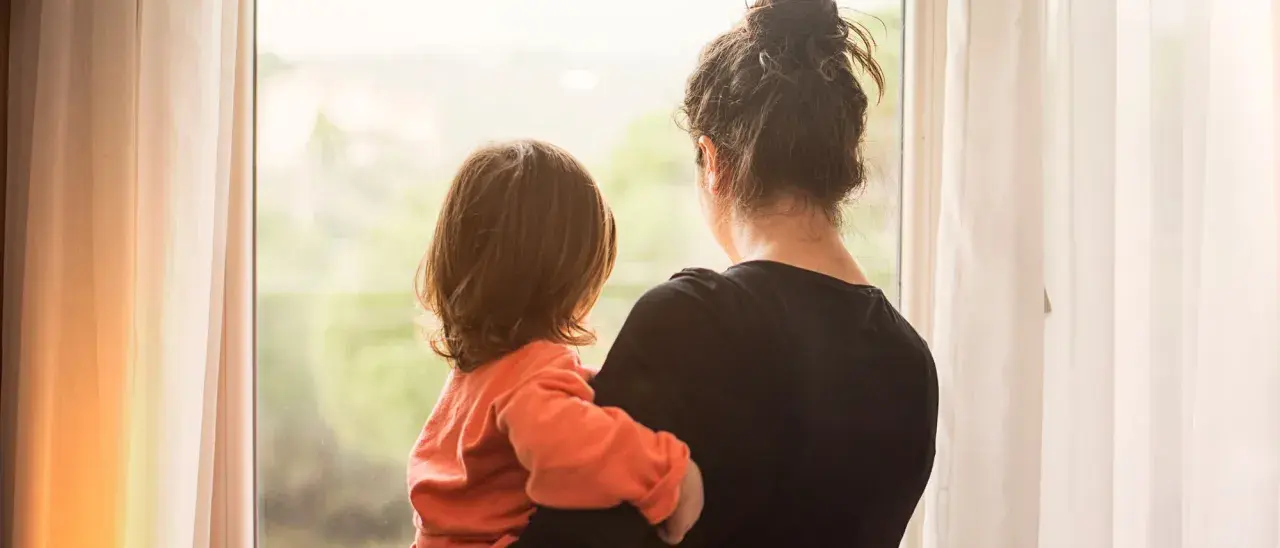 Ein Kind kuschelt sich an seine Mutter, die aus dem Fenster schaut. Die Szene erweckt Gefühle von Geborgenheit, aber auch die leise Angst, die Mutter zu verlieren.
