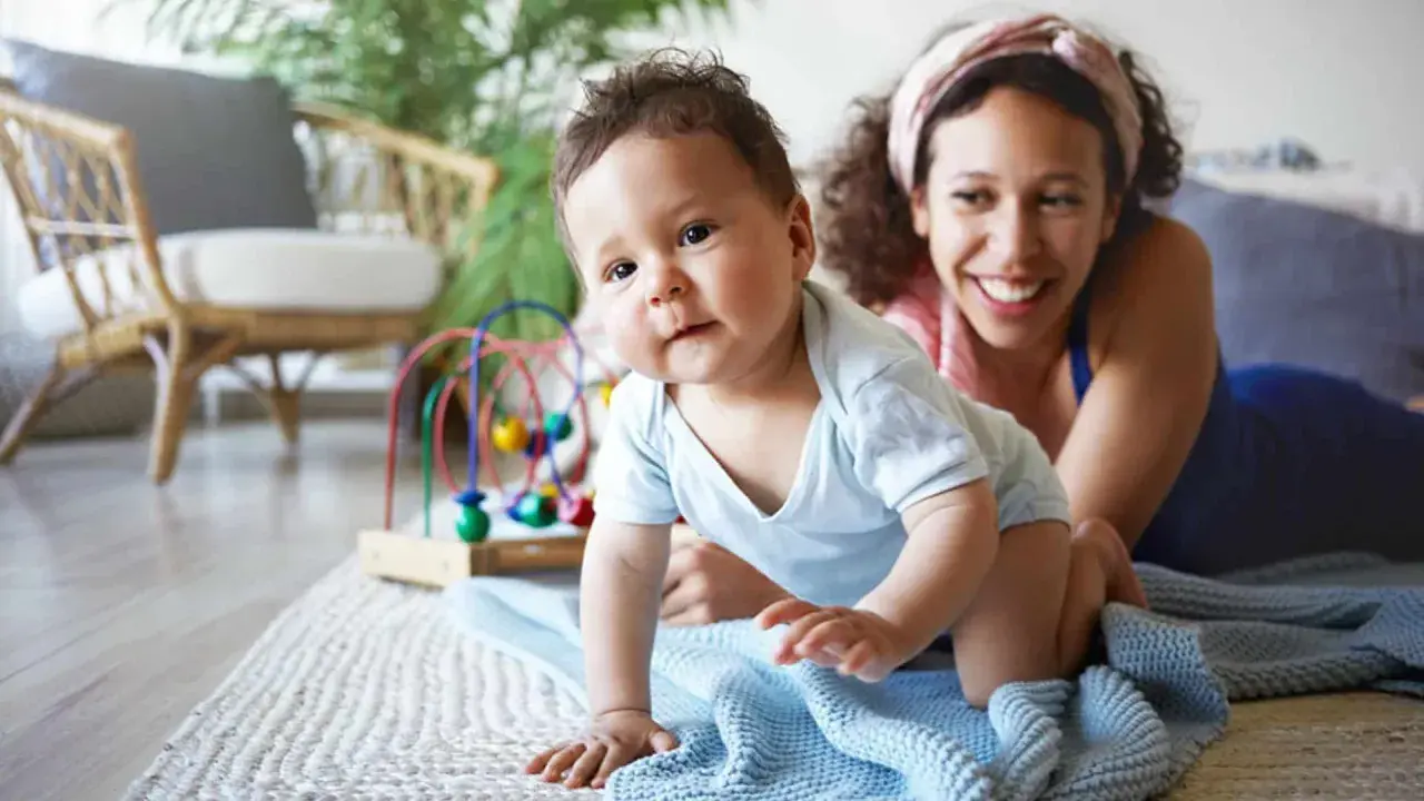 Ein Baby krabbelt neugierig, seine Mutter lächelt. Ein starker Wille zeigt sich schon früh, die Bedeutung des Namens wird gelebt.