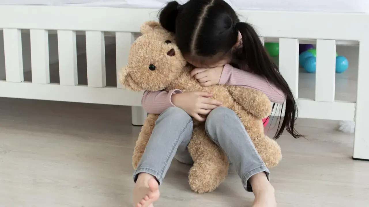 Ein trauriges Kind umarmt seinen Teddybär. Tipps, was tun gegen heimweh kinder, um Trost zu spenden.