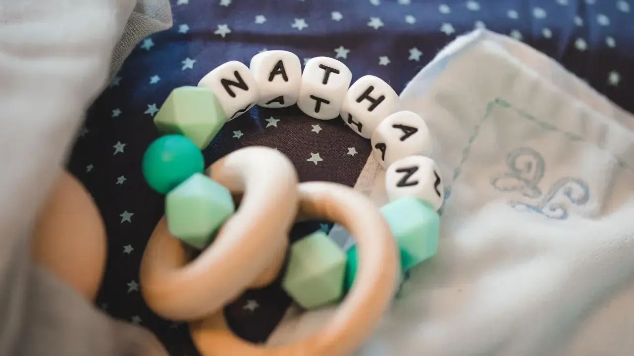 Ein Beißring mit den Buchstaben "NATHAN" und mintgrünen Perlen. Perfekt für super coole Jungennamen!