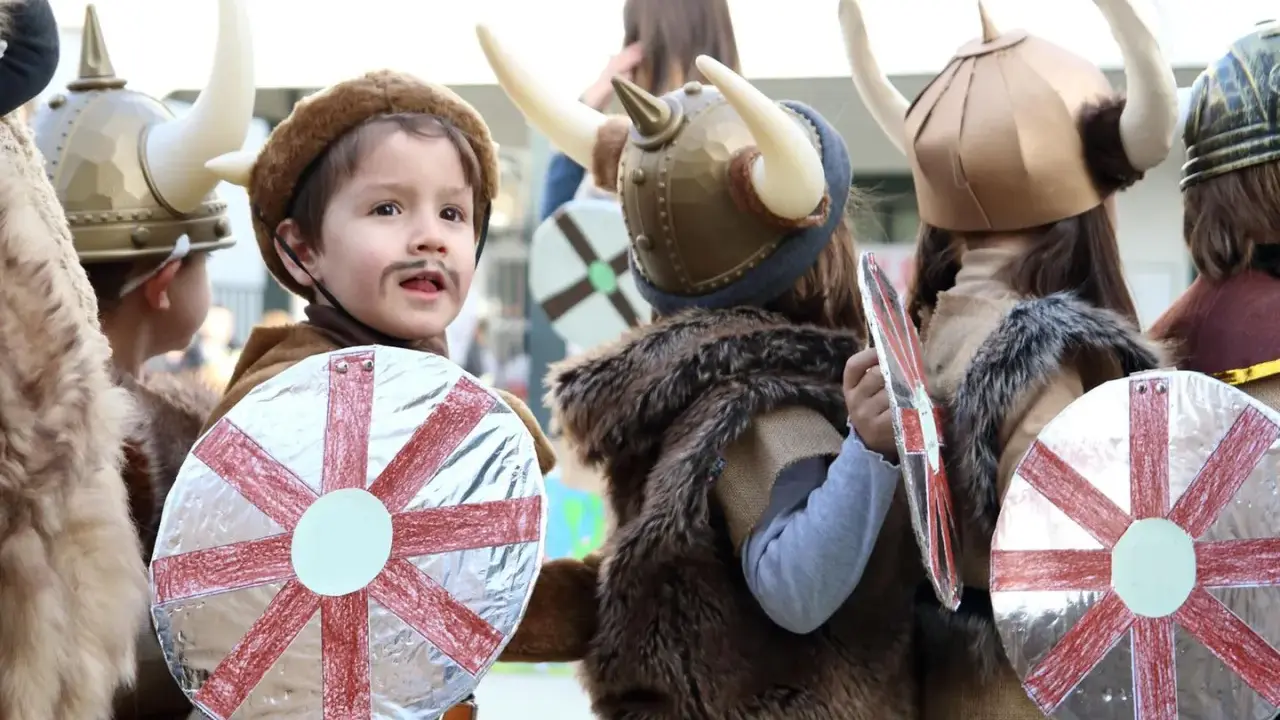 Kinder in Wikingerkostümen mit Hörnerhelmen und Schilden. Vielleicht sind das zukünftige Krieger mit Namen wie Ragnar oder Björn, die sich auf ihre Wikinger-Jungennamen vorbereiten.