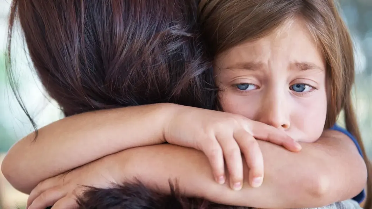 Ein trauriges Kind umarmt seine Mutter. In der Grundschule darf das Kind nicht mitspielen, es fühlt sich ausgeschlossen.