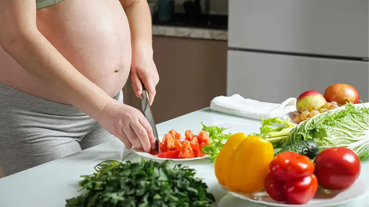 Schwangere bereitet gesunde Mahlzeit zu. Bunte Paprika, Tomaten und frisches Gemüse für eine gute Ernährung während der Schwangerschaft.