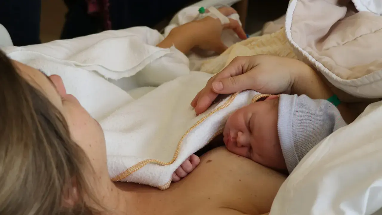 Ein kleiner Sternengucker-Baby schläft auf der Brust seiner Mutter, eingewickelt in eine weiche Decke.