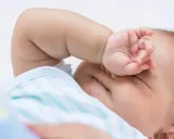 Baby im REM-Schlaf, die Hand vor den Augen, träumt süß.