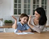 Mutter und Kind geben sich High Five. Das Kind will nicht lernen, aber die Mutter motiviert es.