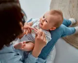 Ein Baby liegt auf dem Schoß einer Person. Vielleicht sucht die Person nach Inspiration für Jungennamen aus der Bibel.