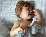 Ein weinendes Kind, 1 Jahr alt, in der Trotzphase, hält seinen Kuschelhasen.