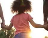 Kind hält Hände von Eltern. Die gesetzliche Regelung Kinderbetreuung Trennung soll das Wohl des Kindes sichern.