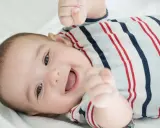 Ein lächelnder Junge in gestreiftem Strampler. Vielleicht ein zukünftiger Träger moderner arabischer Namen, Jungen wie Omar oder Karim.