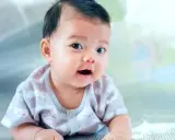 Ein Baby mit dunklem Haar liegt auf dem Bauch. Seine Eltern überlegen, welche vietnamesischen Namen am besten zu ihm passen.