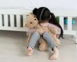 Ein trauriges Kind umarmt seinen Teddybär. Tipps, was tun gegen heimweh kinder, um Trost zu spenden.