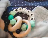 Ein Beißring mit den Buchstaben "NATHAN" und mintgrünen Perlen. Perfekt für super coole Jungennamen!