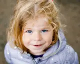 Ein blondes Mädchen mit blauen Augen lächelt. Ihr Haar ist zerzaust, wie bei vielen norddeutschen Frauennamen, die oft eine natürliche Schönheit widerspiegeln.