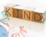 Holzklötze mit den Buchstaben K, I, N, D und einem Fragezeichen. Daneben liegt ein Baby. Ist das dritte Kind eine falsche Entscheidung?