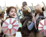 Kinder in Wikingerkostümen mit Hörnerhelmen und Schilden. Vielleicht sind das zukünftige Krieger mit Namen wie Ragnar oder Björn, die sich auf ihre Wikinger-Jungennamen vorbereiten.