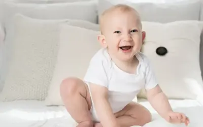 Ein strahlendes Baby, ein echtes Kind der Sonne, sitzt auf einem Bett. Elias' Lachen ist ansteckend.