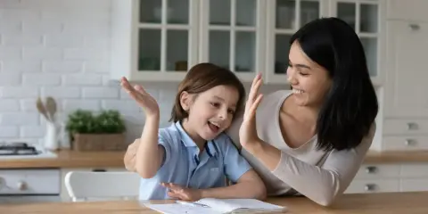 Mutter und Kind geben sich High Five. Das Kind will nicht lernen, aber die Mutter motiviert es.