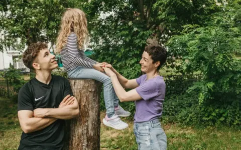 Ein junger Mann schaut zu seiner Mutter, die mit seiner kleinen Schwester auf einem Baumstumpf sitzt. Vielleicht denkt er, wenn der Sohn die falsche Freundin hat, ist die Familie trotzdem da.