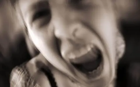 Verzweifeltes Gesicht, das schreit. Die Frage "warum bin ich so aggressiv zu meiner familie" hallt in der Stille wider.