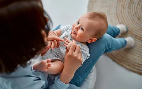 Ein Baby liegt auf dem Schoß einer Person. Vielleicht sucht die Person nach Inspiration für Jungennamen aus der Bibel.