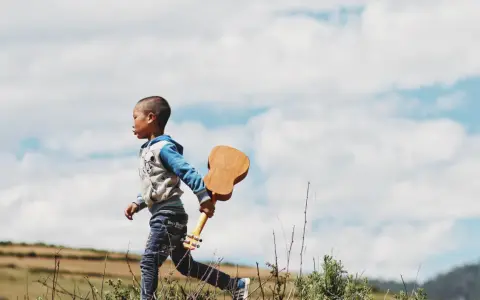 Ein kleiner Junge, vielleicht 18 Monate, rennt mit einer Ukulele durch die Natur. Ein sehr anstrengender, aber glücklicher Moment.