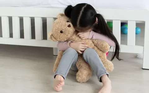Ein trauriges Kind umarmt seinen Teddybär. Tipps, was tun gegen heimweh kinder, um Trost zu spenden.
