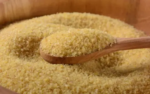 Eine Holzlöffel voller Bulgur, ein gesundes Getreide, das oft in der Ernährung während der Schwangerschaft empfohlen wird.