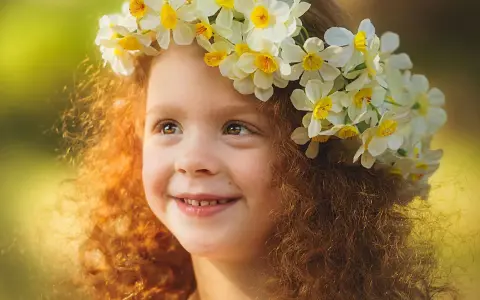 Ein Mädchen mit roten Locken und einem Blumenkranz im Haar, das an keltische Namen weiblich erinnert.