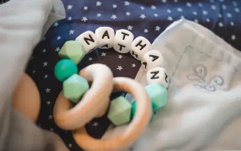 Ein Beißring mit den Buchstaben "NATHAN" und mintgrünen Perlen. Perfekt für super coole Jungennamen!