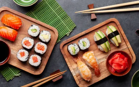Frischer roher Fisch stillt den Appetit auf Sushi. Nigiri mit Lachs, Maki-Rollen mit Avocado und Garnelen-Sushi auf Holzbrettern.