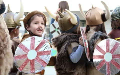 Kinder in Wikingerkostümen mit Hörnerhelmen und Schilden. Vielleicht sind das zukünftige Krieger mit Namen wie Ragnar oder Björn, die sich auf ihre Wikinger-Jungennamen vorbereiten.