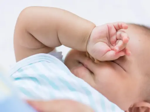 Baby im REM-Schlaf, die Hand vor den Augen, träumt süß.