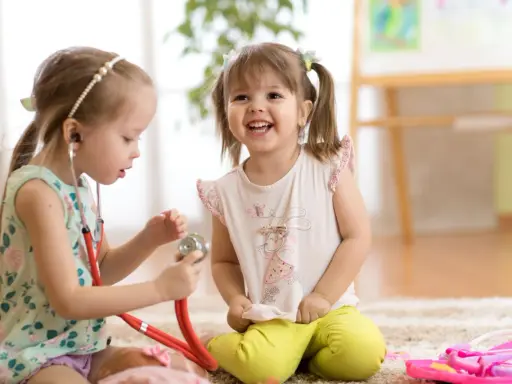 Zwei Mädchen spielen Arzt. Das eine Kind, etwa 7 Jahre alt, untersucht das andere mit einem Stethoskop. Ein spielerischer Einblick in die sexuelle Entwicklung eines Kindes.
