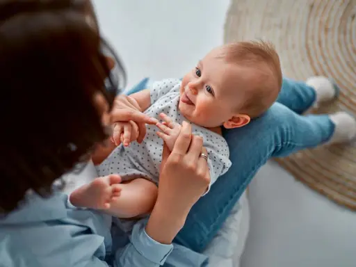 Ein Baby liegt auf dem Schoß einer Person. Vielleicht sucht die Person nach Inspiration für Jungennamen aus der Bibel.