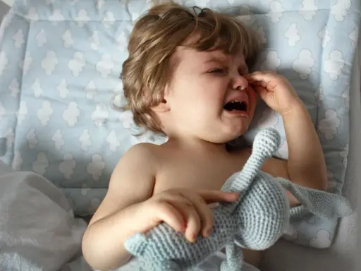 Ein weinendes Kind, 1 Jahr alt, in der Trotzphase, hält seinen Kuschelhasen.