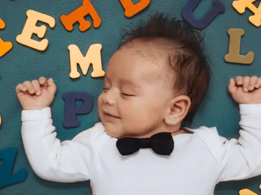 Schlafender Junge mit Fliege, umgeben von bunten Buchstaben. Vielleicht ein zukünftiger Paul oder Peter?