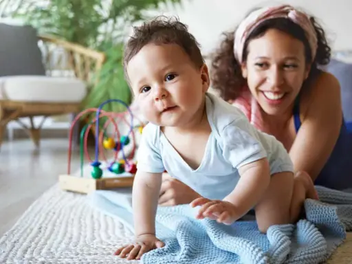 Ein Baby krabbelt neugierig, seine Mutter lächelt. Ein starker Wille zeigt sich schon früh, die Bedeutung des Namens wird gelebt.