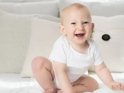Ein strahlendes Baby, ein echtes Kind der Sonne, sitzt auf einem Bett. Elias' Lachen ist ansteckend.