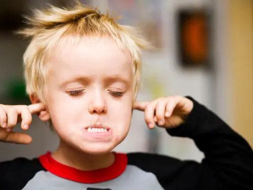 Ein Junge mit blonden Haaren stopft sich Finger in die Ohren, die Augen geschlossen, als ob er nichts hören will. Er verweigert alles.
