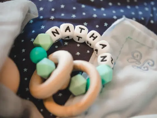 Ein Beißring mit den Buchstaben "NATHAN" und mintgrünen Perlen. Perfekt für super coole Jungennamen!