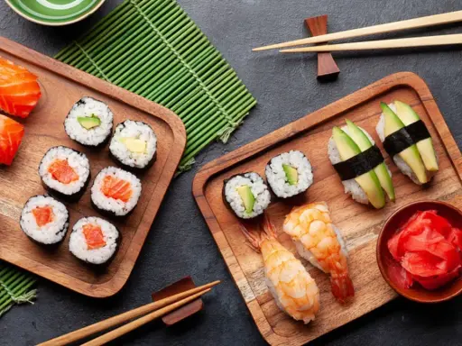 Frischer roher Fisch stillt den Appetit auf Sushi. Nigiri mit Lachs, Maki-Rollen mit Avocado und Garnelen-Sushi auf Holzbrettern.