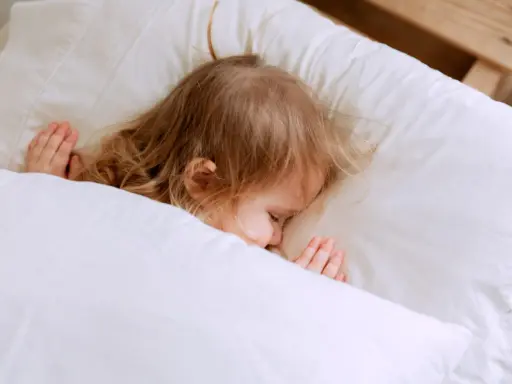Kleines Kind schläft friedlich im Bett. Ab wann schlafen Kinder alleine ein? Diese süße Szene zeigt einen friedlichen Schlaf.