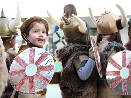 Kinder in Wikingerkostümen mit Hörnerhelmen und Schilden. Vielleicht sind das zukünftige Krieger mit Namen wie Ragnar oder Björn, die sich auf ihre Wikinger-Jungennamen vorbereiten.