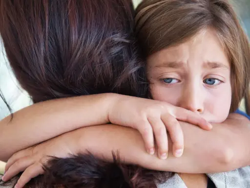 Ein trauriges Kind umarmt seine Mutter. In der Grundschule darf das Kind nicht mitspielen, es fühlt sich ausgeschlossen.